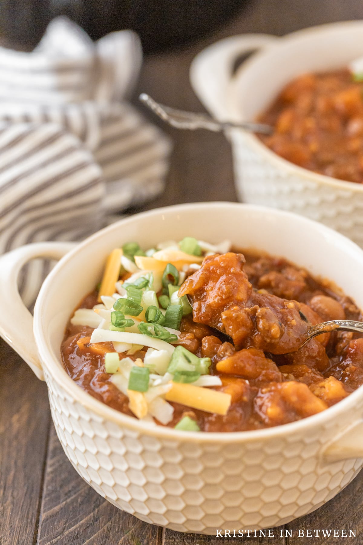 A bowl of chili with a spoonful laying on top of it.
