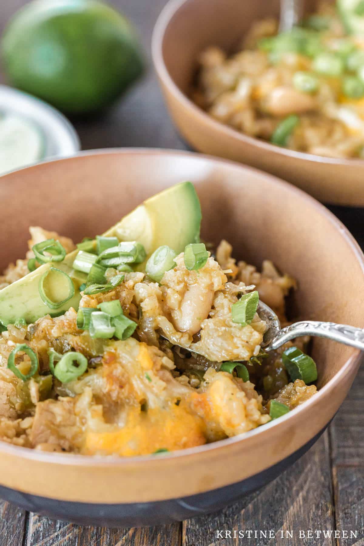 A bowl of chicken chili with a bite on a spoon.