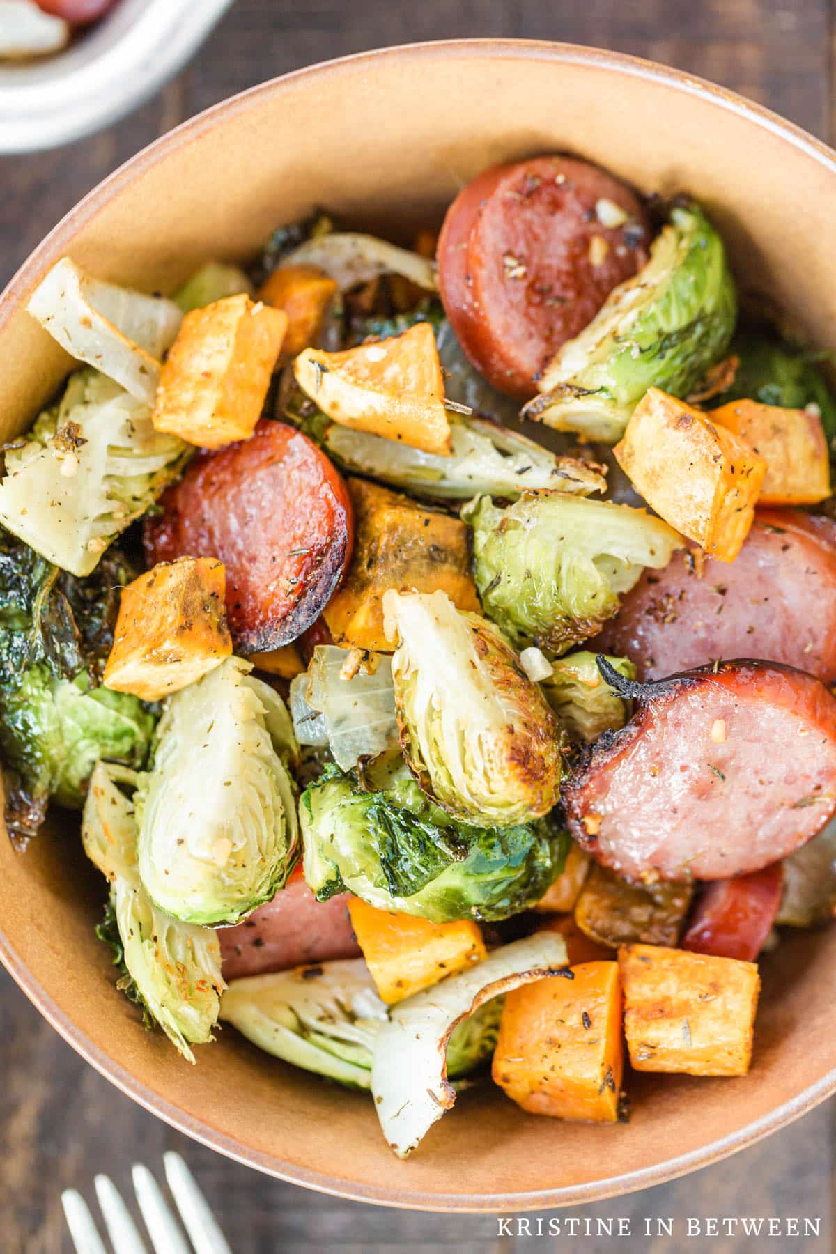 A sheet pan dinner in a bowl with a fork laying next to it.