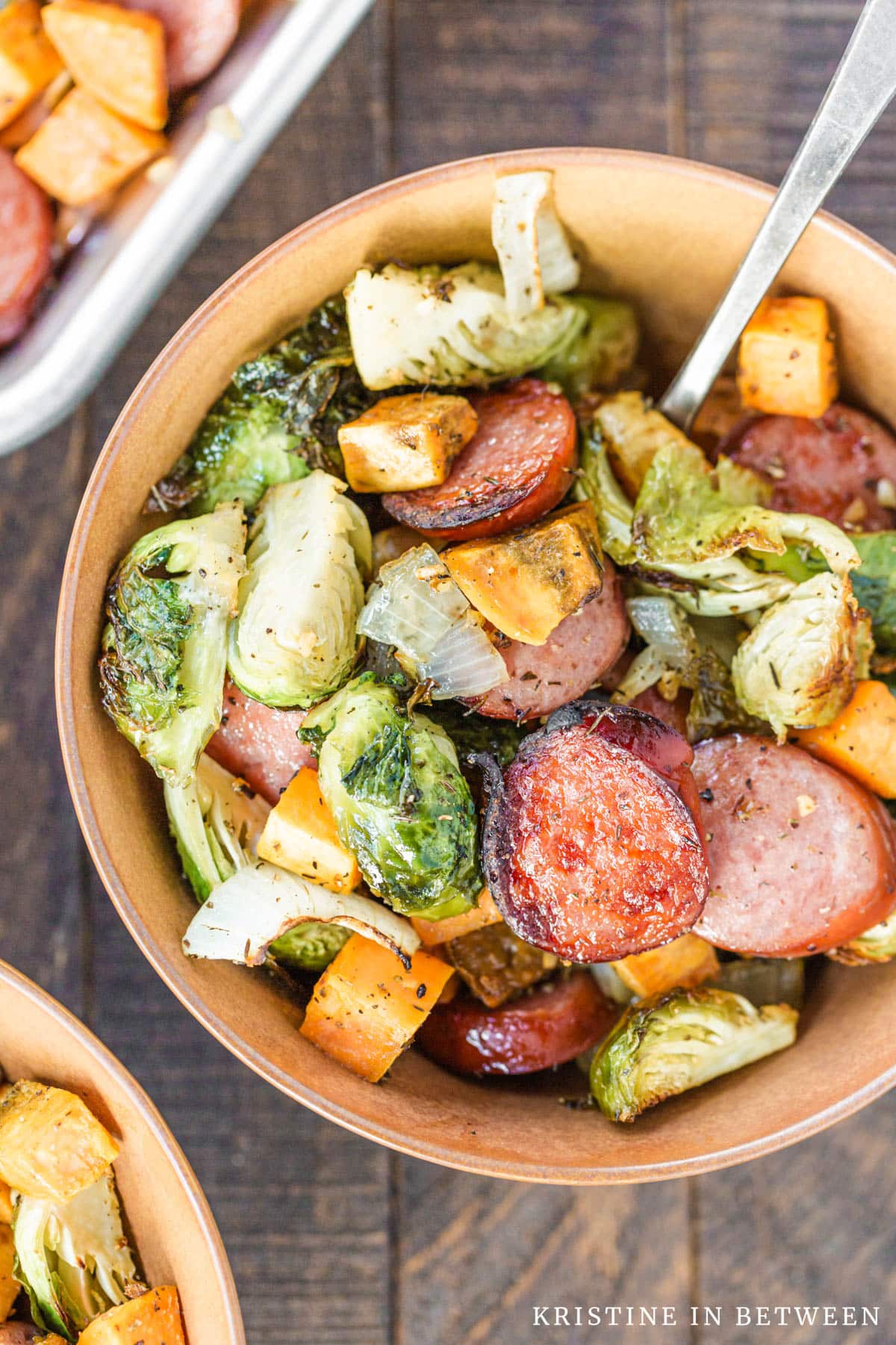 A bowl of Kielbasa sausage and Brussel sprouts with a fork in it.