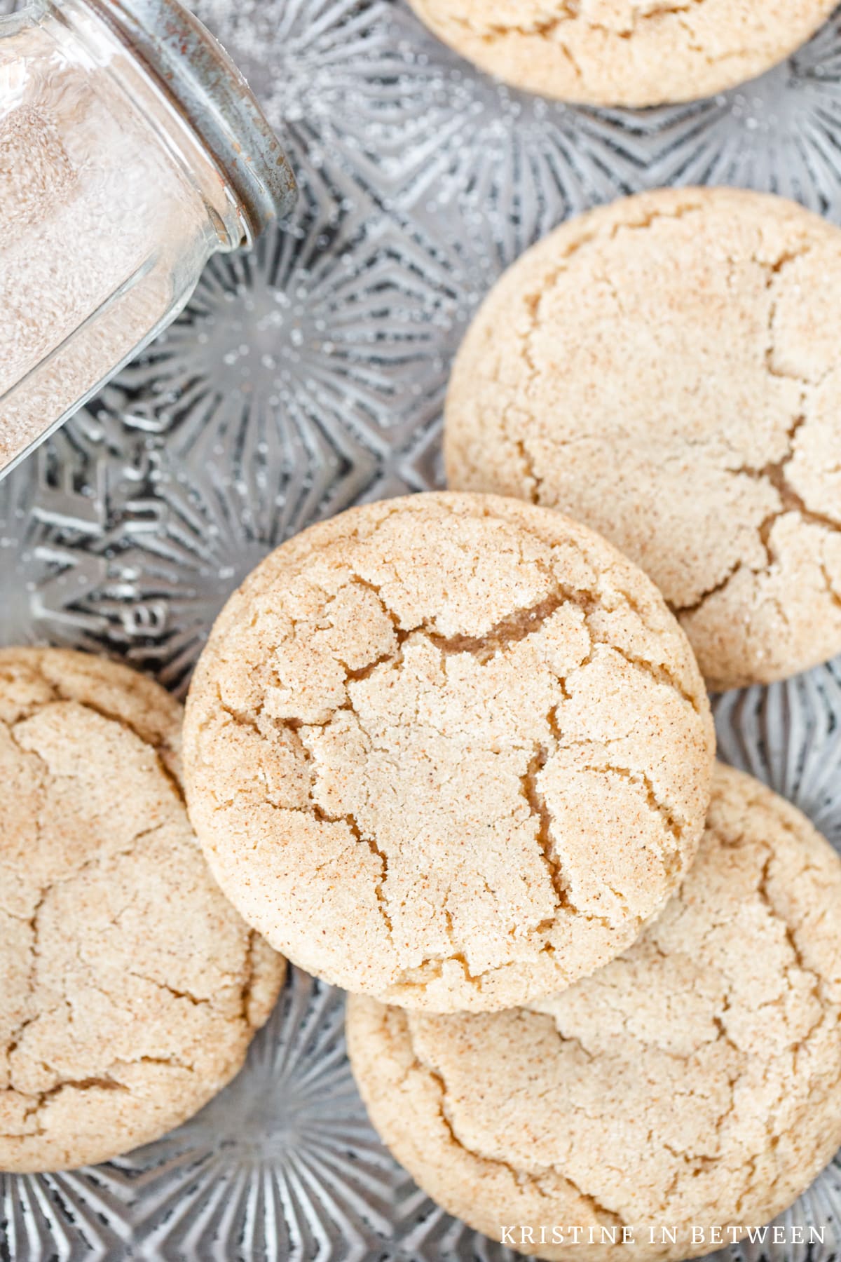 Cookies laying on an antique cookie sheet with a shaker full of sugar laying with them.