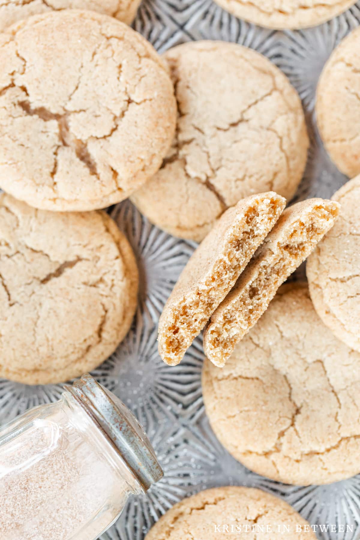 Cookies laying on a cookie sheet with one broken in half to show the inside of the cookie.