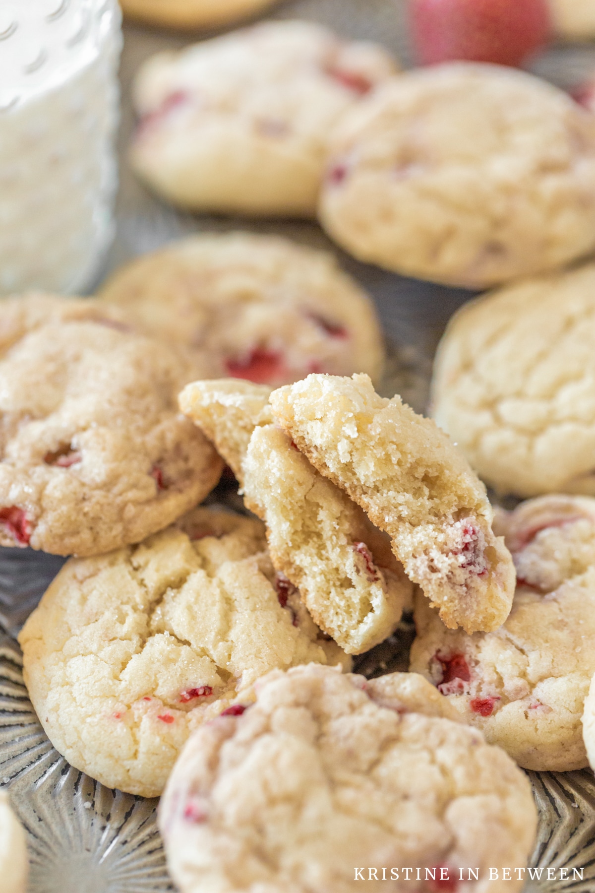 Cookies laying on an old cookie sheet with one broken in half to show the crumbs.