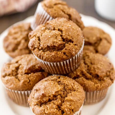 A muffin plate full of gingerbread muffins with a cup of coffee in the background.