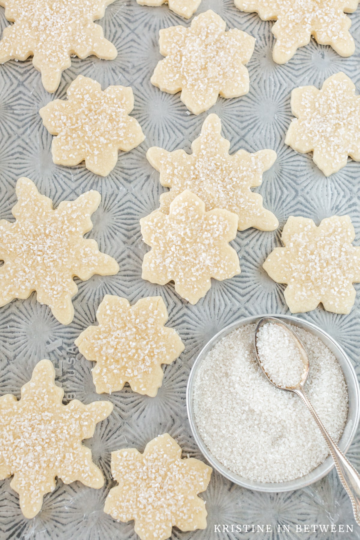 A tray of sugar cookies cut out into snowflakes and dusted with sugar.