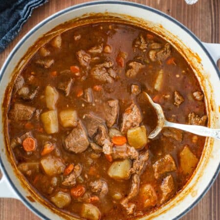 A pot of Dutch oven Irish stew with an old spoon sitting in it.
