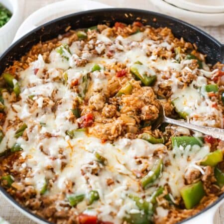 Stuffed pepper skillet with melted cheese on top and a spoon in the center.
