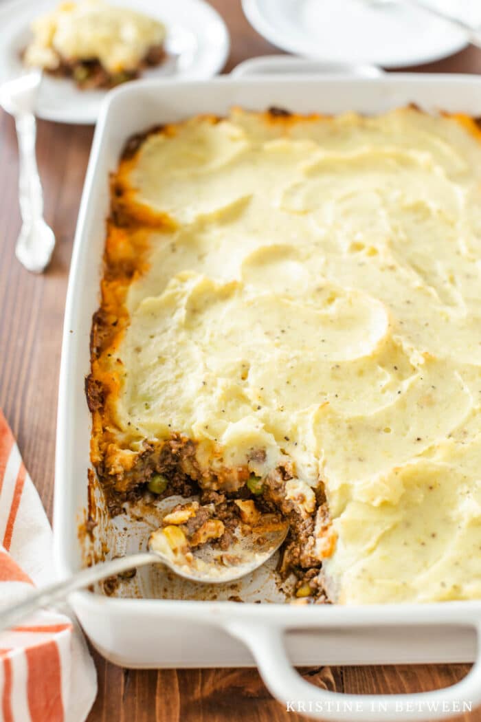 A pan of shepherd's pie with a spoonful removed and a spoon in the pan.