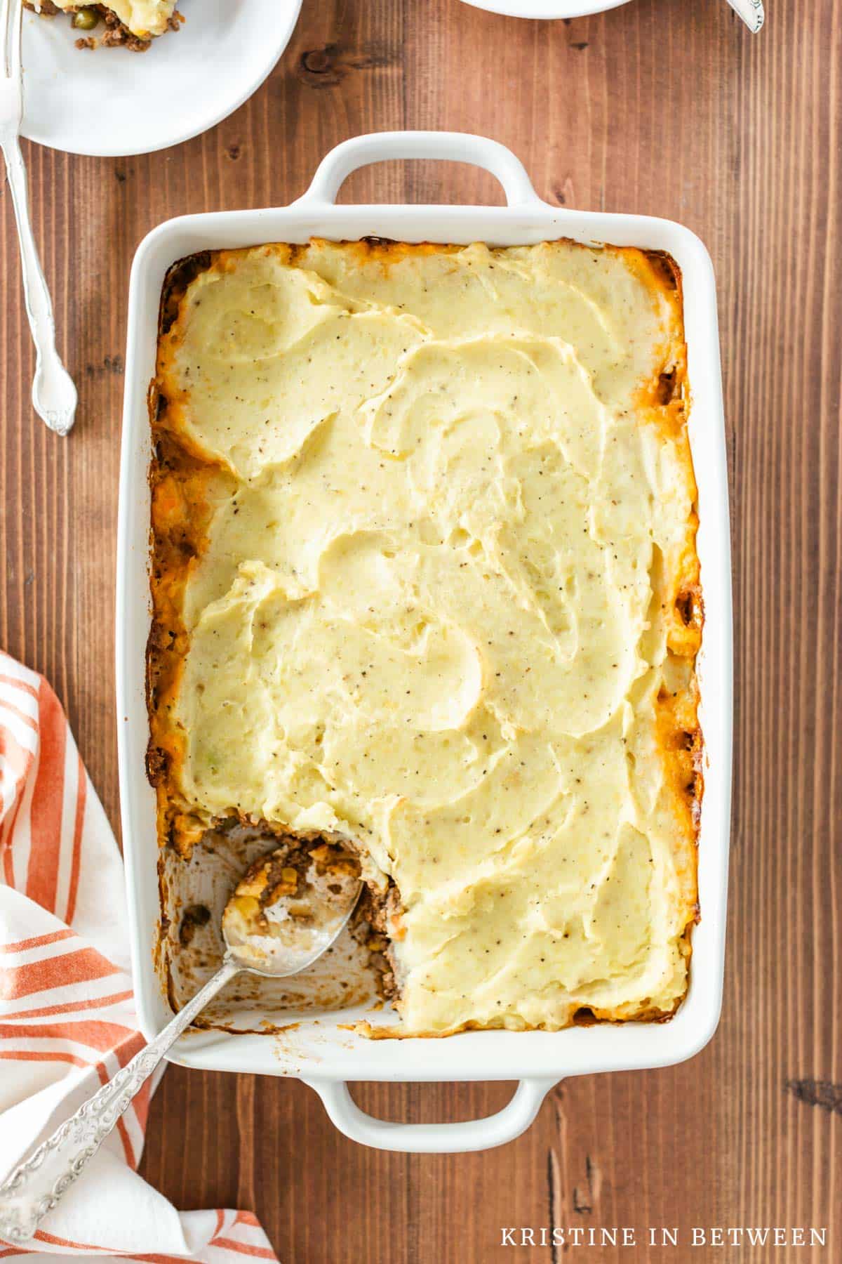 A pan of shepherd's pie with a spoonful removed and a plate in the background.