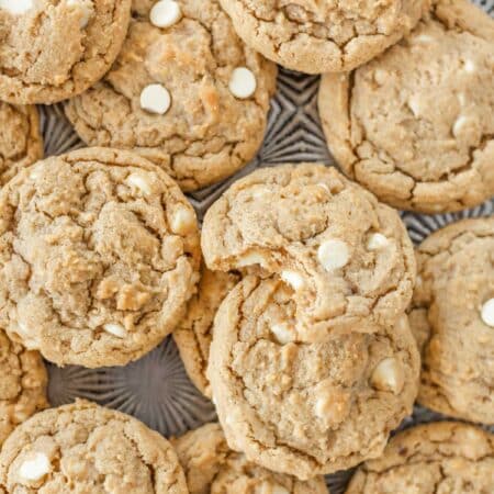 Cookies piled upon a baking sheet with the top one missing a bite.