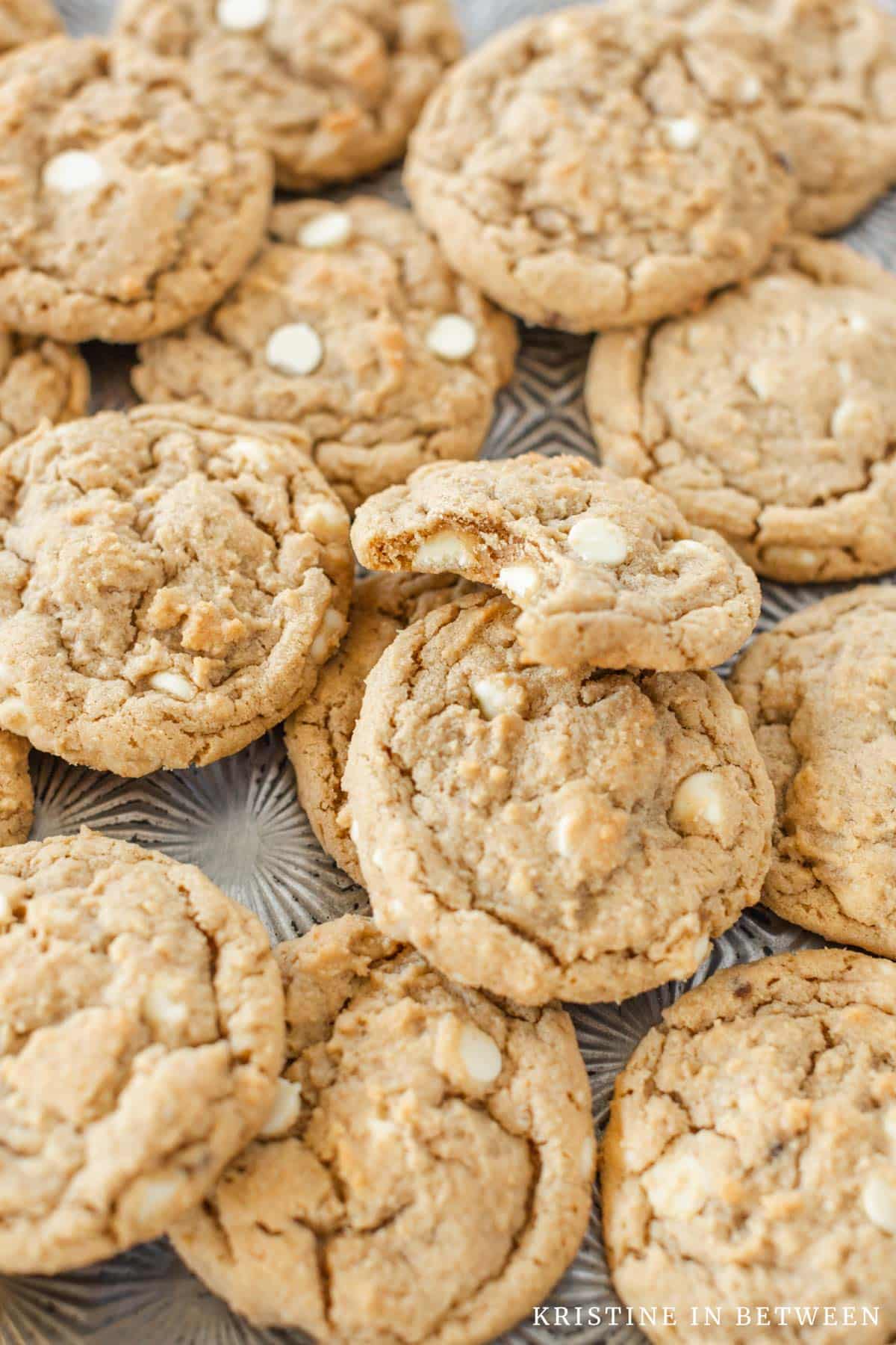 Cookies piled upon a baking sheet with the top one missing a bite.