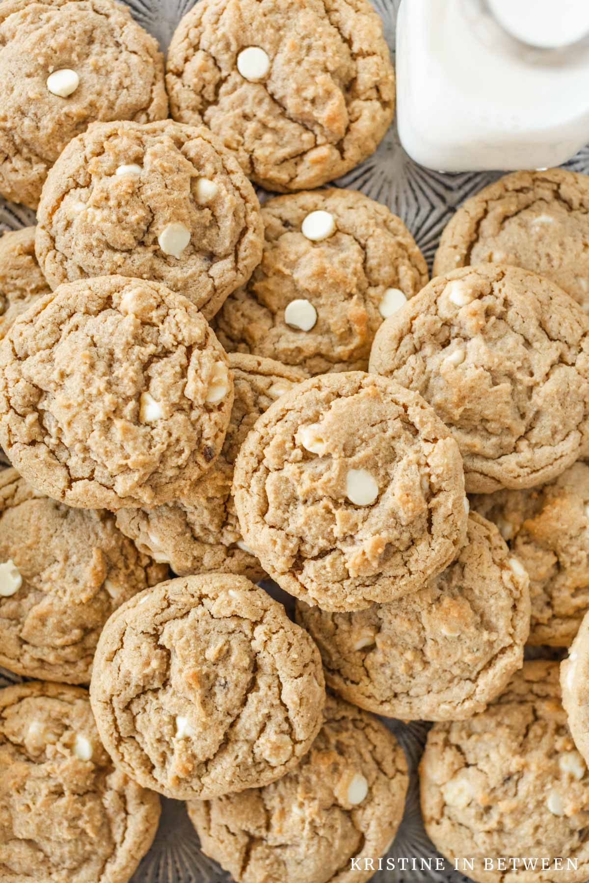 Peanut butter cookies piled up on an antique cookie sheet with a small glass of milk.