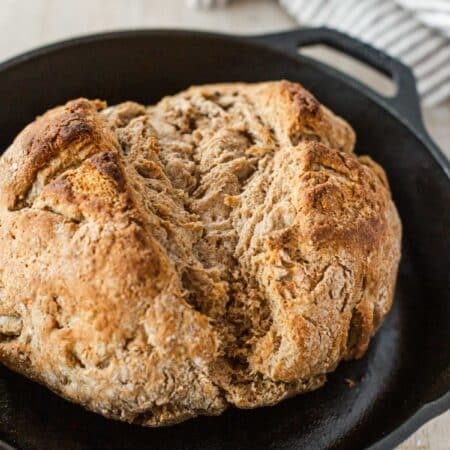 A baked loaf of Irish brown bread in a cast iron skillet.