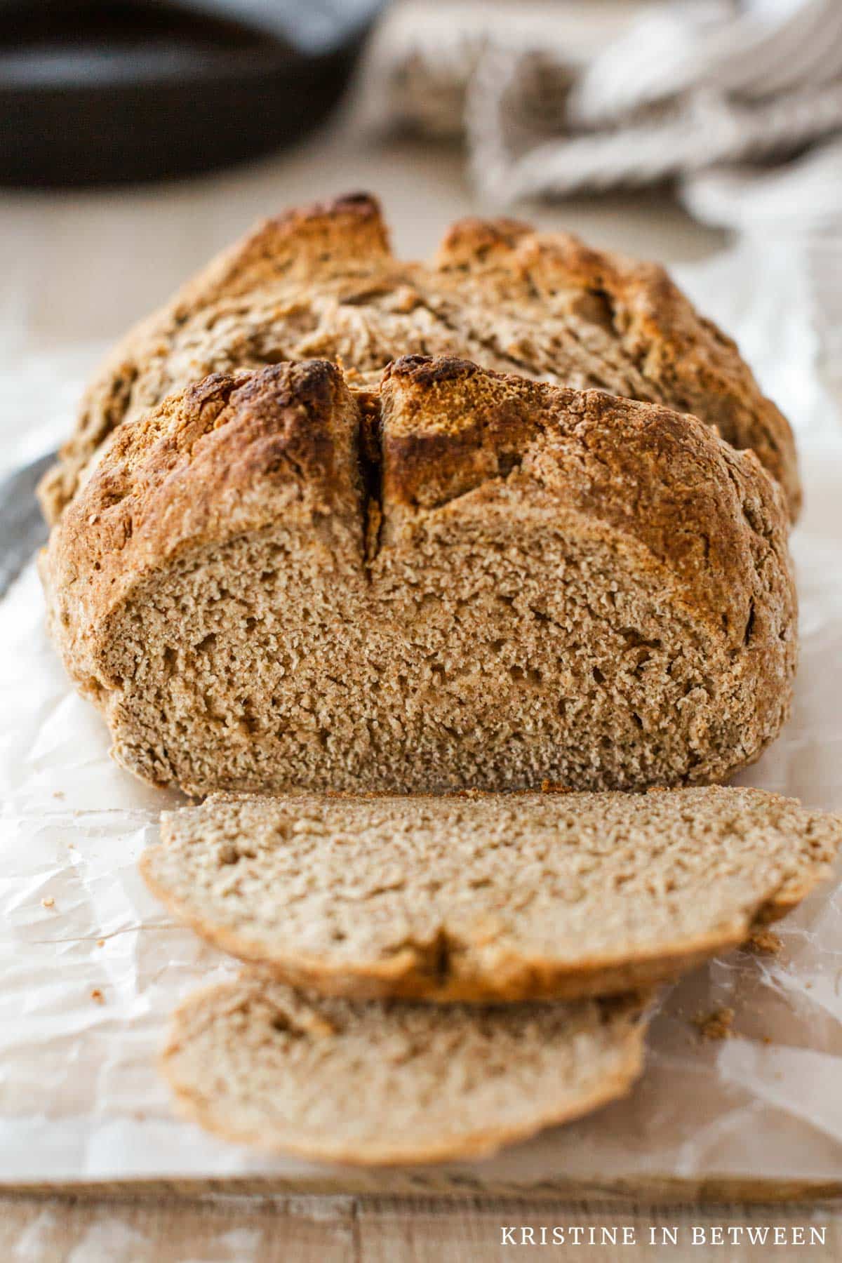 A loaf of brown bread with the end cut off to show the inside of the bread.