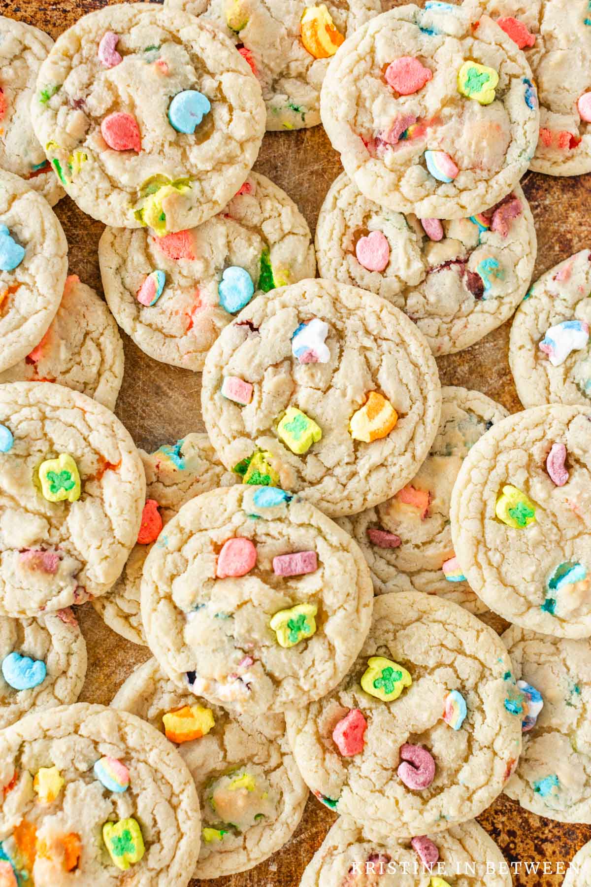 Lucky Charms sugar cookies stacked upon an old baking sheet.