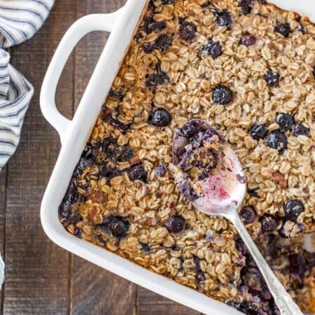 Baked blueberry pecan oatmeal in a casserole dish with a small plate next to it.