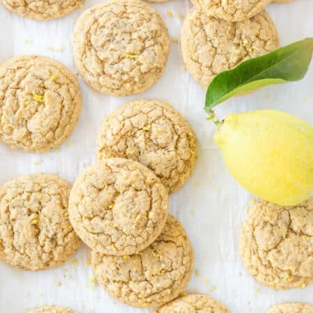 Lemon poppy seed cookies laying on a baking sheet with a lemon.