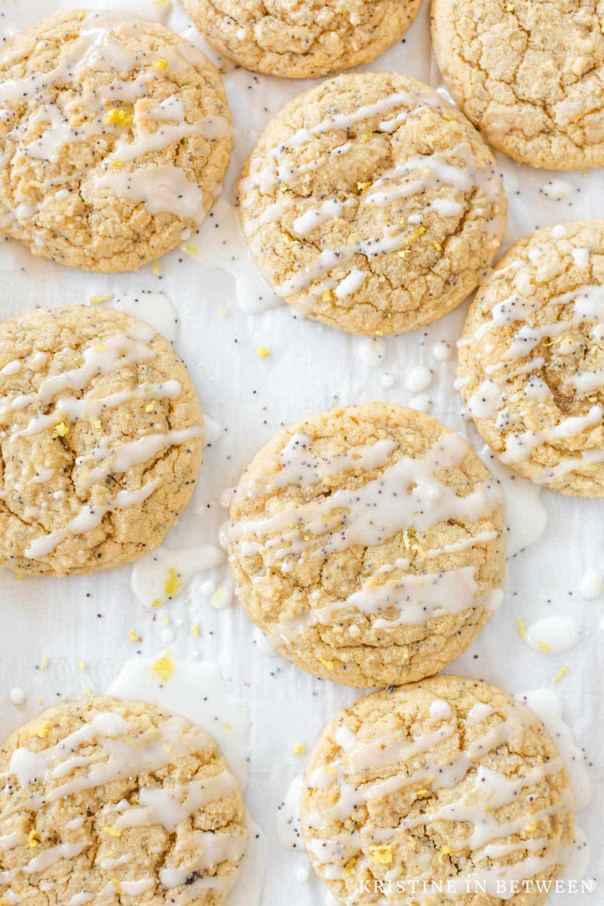 Frosted lemon poppy seed cookies laying on a baking sheet.