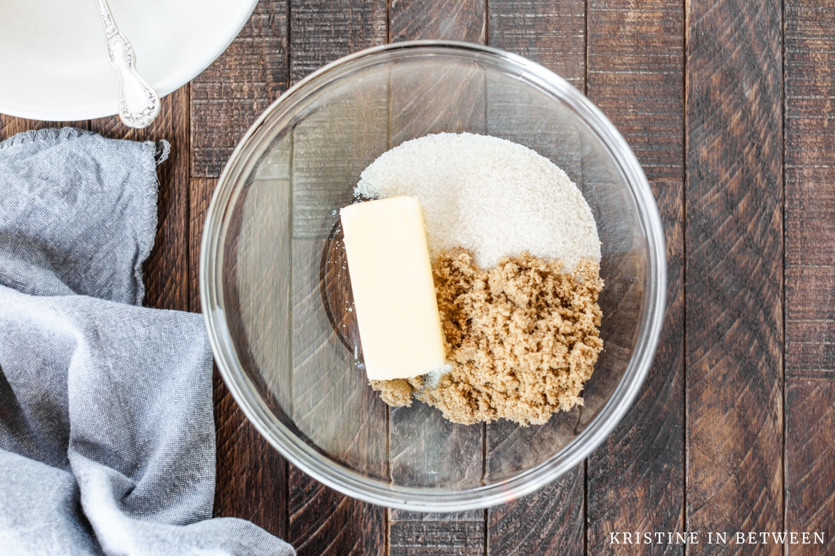 A glass bowl with butter, sugar, and brown sugar sitting in it.