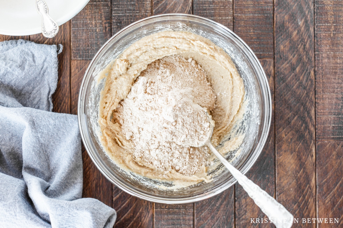 White whole wheat flour sitting in a bowl of creamed butter and sugar.