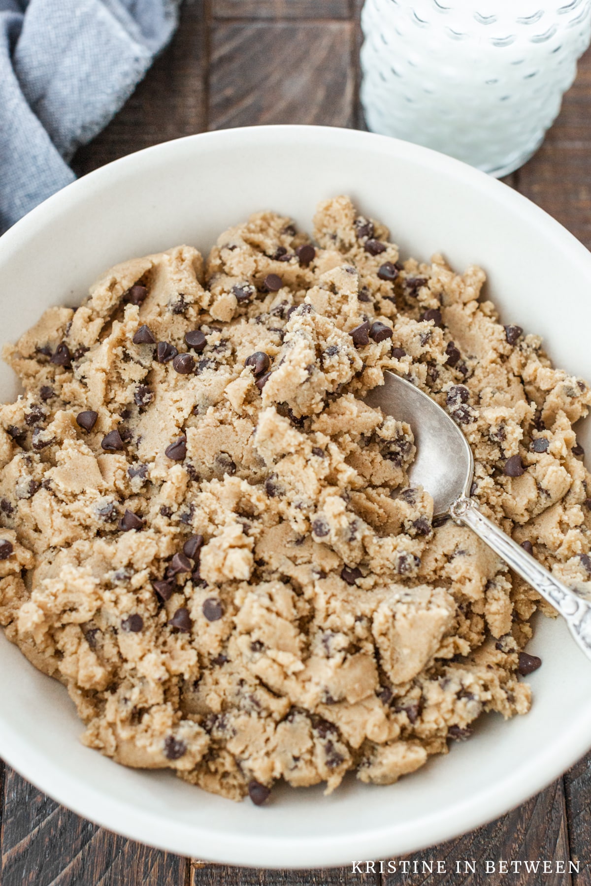 A bowl of chocolate chip edible cookie dough with a spoon in it.
