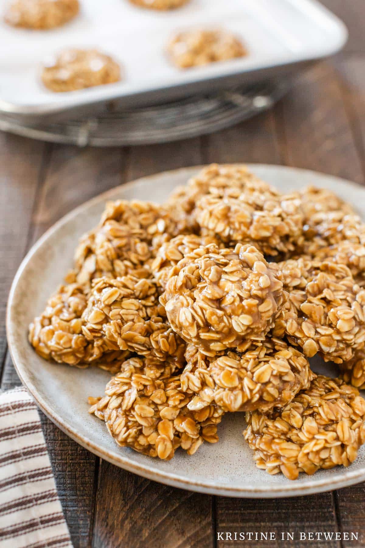 A plate full of no-bake cookies with more sitting on a baking tray in the background.