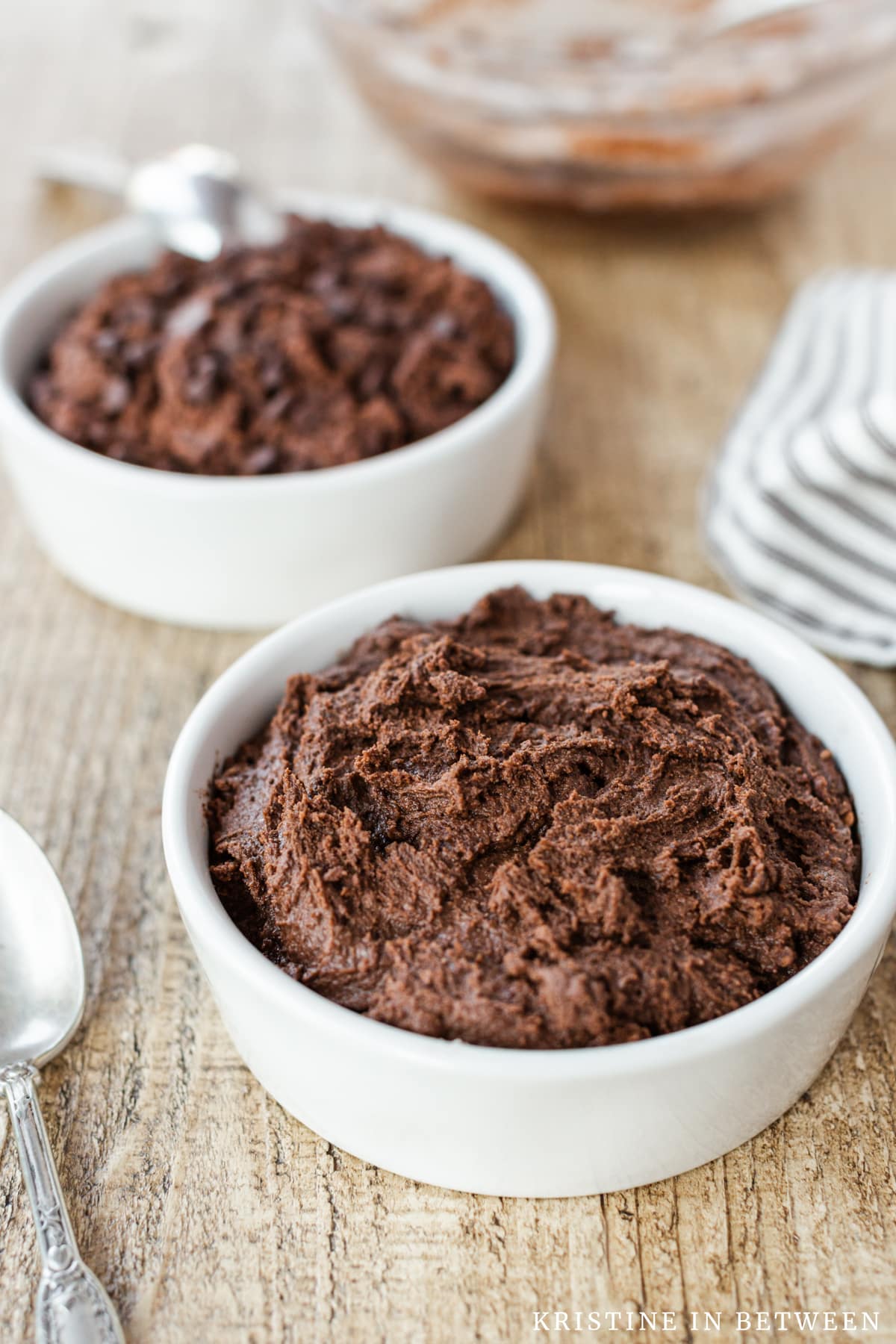 Chocolate edible cookie dough sitting in white bowls with spoons.