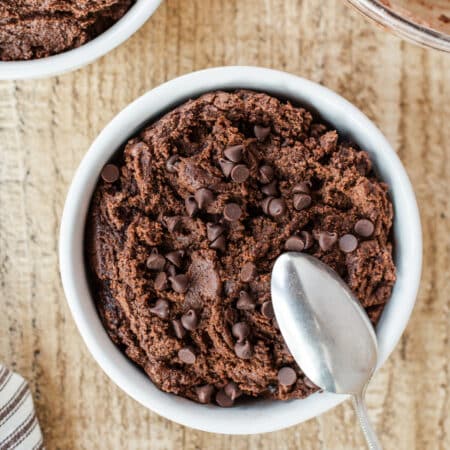 A bowl of edible chocolate cookie dough with a spoon in it.