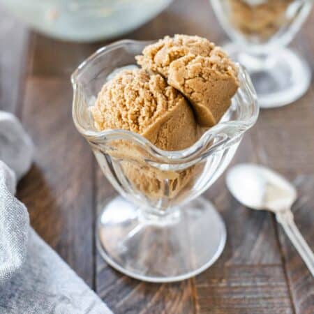 A sundae cup filled with edible peanut butter cookie dough with a spoon in it.