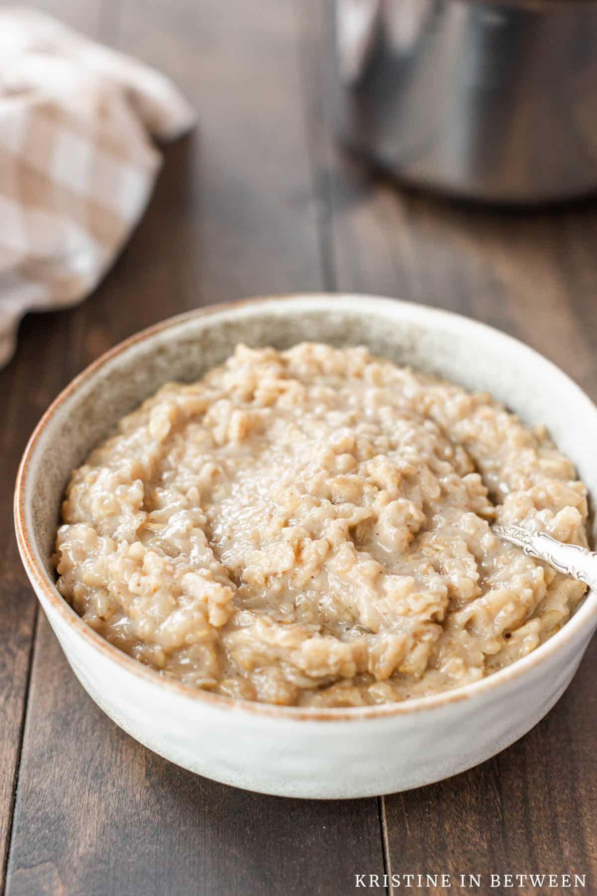 A bowl of plain oatmeal with a spoon in it.