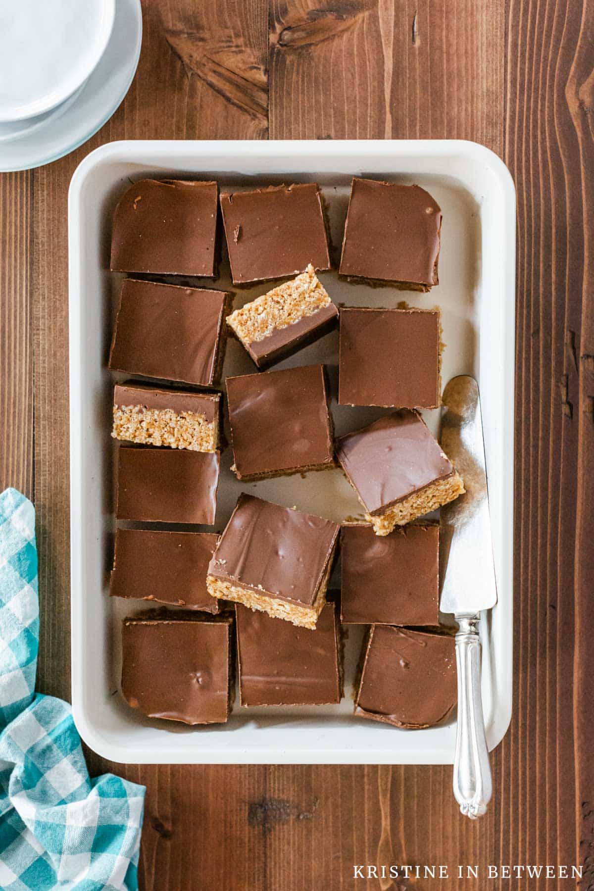 Scotcheroo bars cut into squares in a baking pan with a spatula laying next to them.