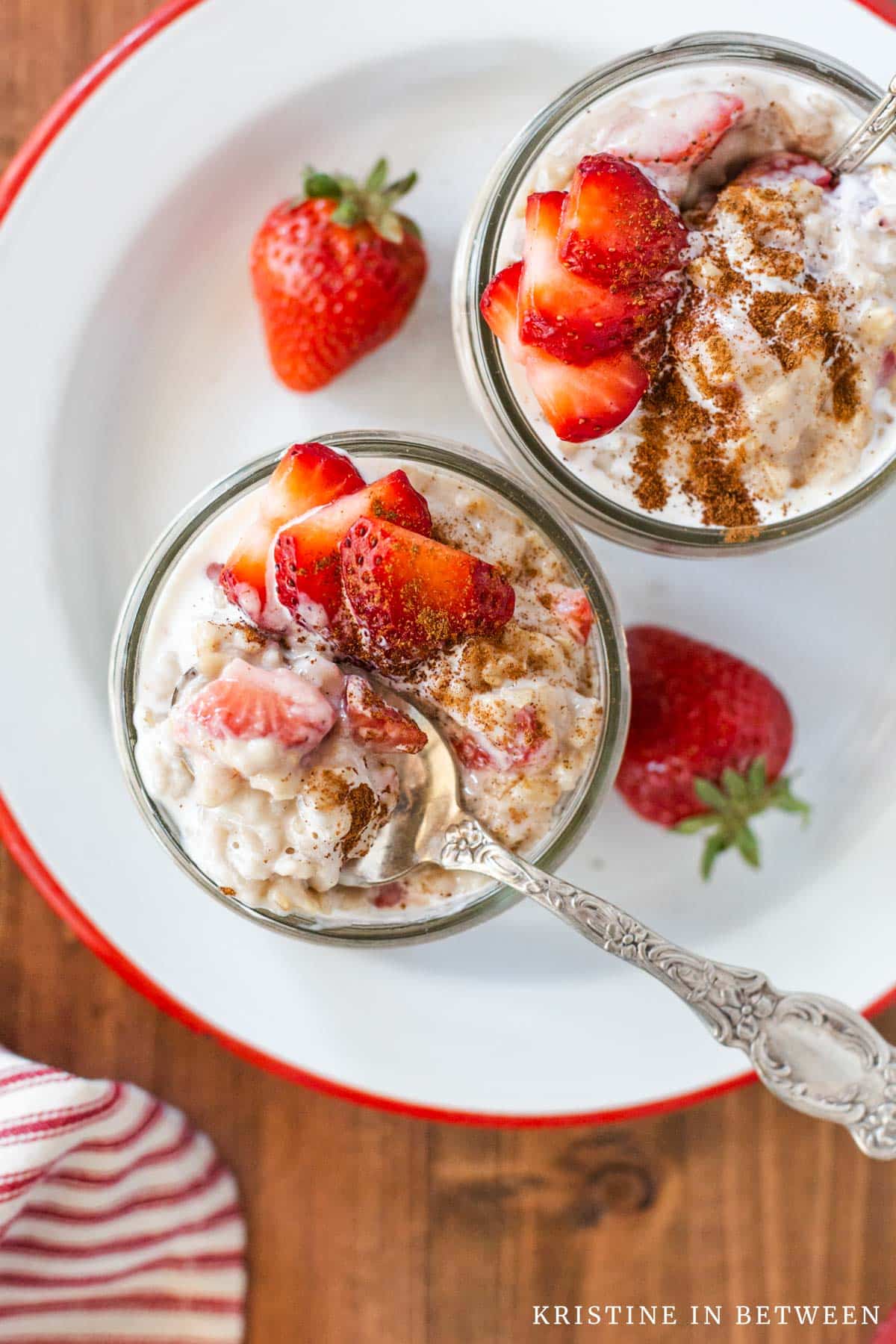 A bite of oatmeal on a spoon with strawberries, cream, and cinnamon.