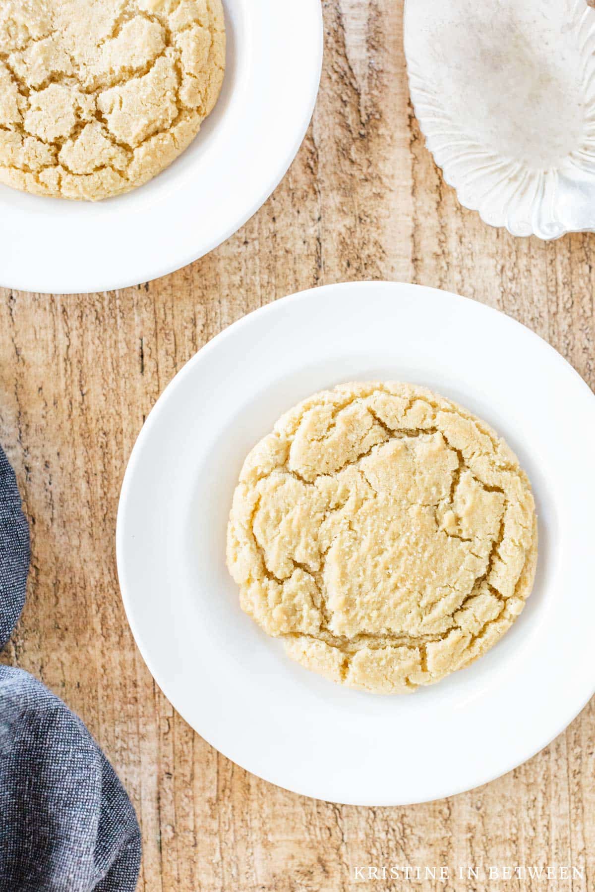 Two sugar cookies sitting on white plates with a spatula next to them.