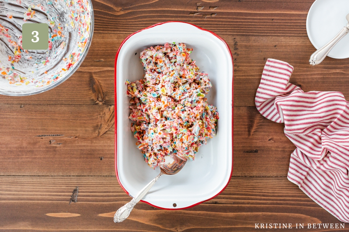 Fruity Pebbles Krispie treats spooned into a metal dish, ready for spreading.