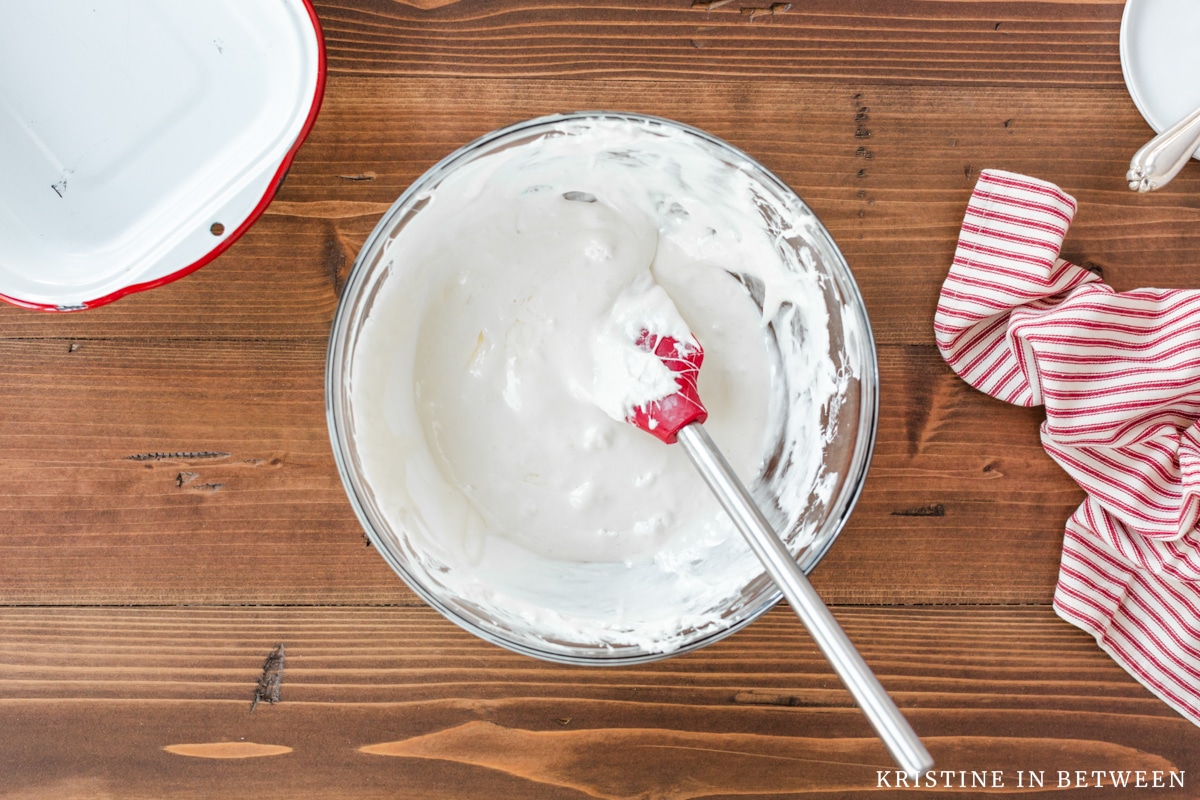 Melted marshmallows and butter in a glass bowl with a rubber spatula.