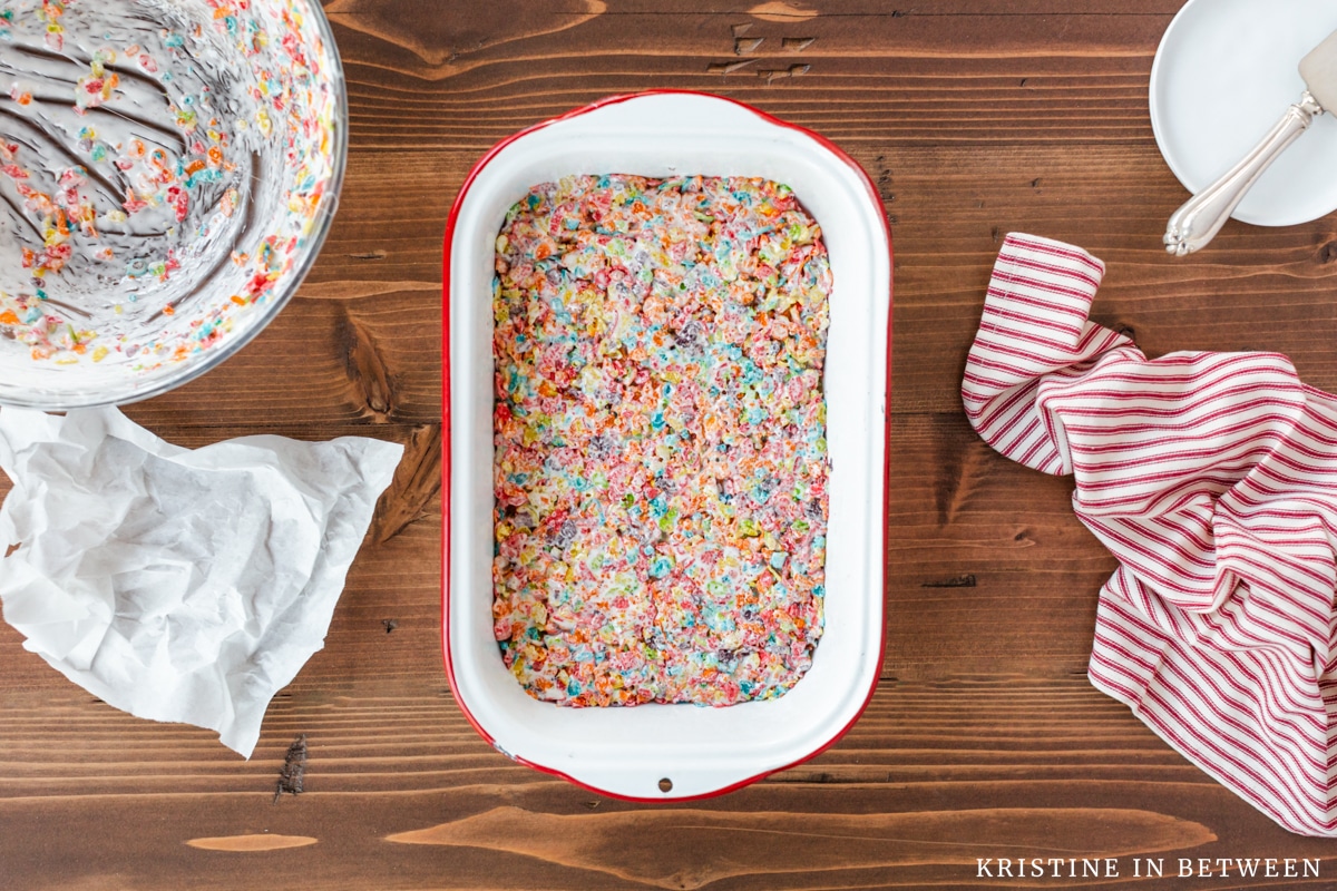 Fruity Pebbles Krispie treats in a tin dish smoothed out and ready for slicing.