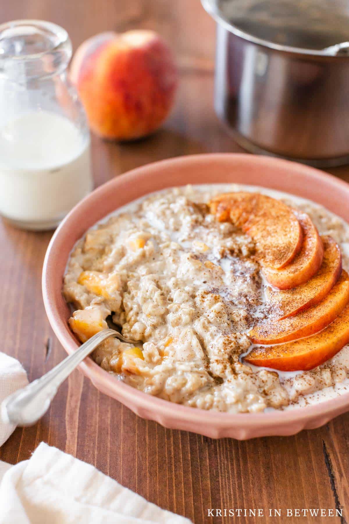 Peaches and cream oatmeal in a bowl with a spoon.