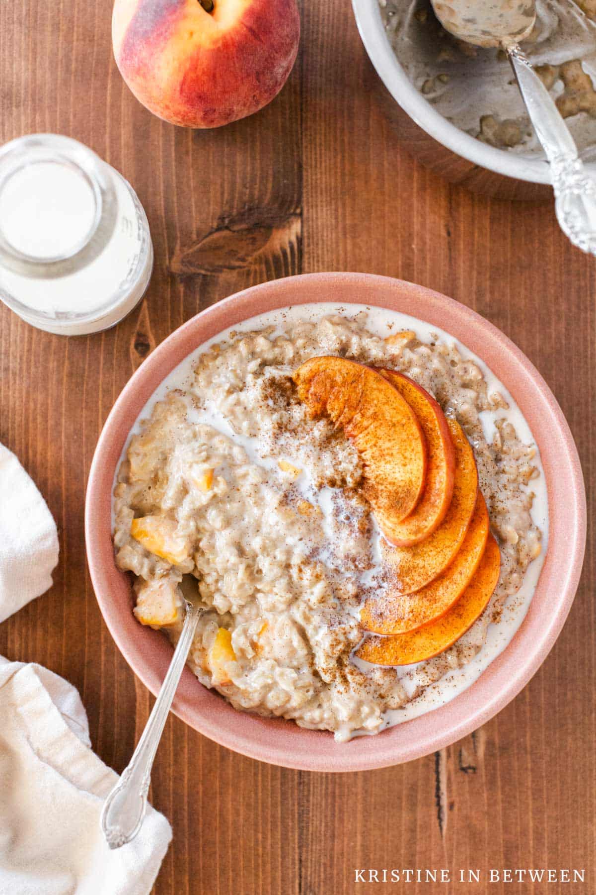A bowl of oatmeal with milk drizzled over the top and a spoon in it.