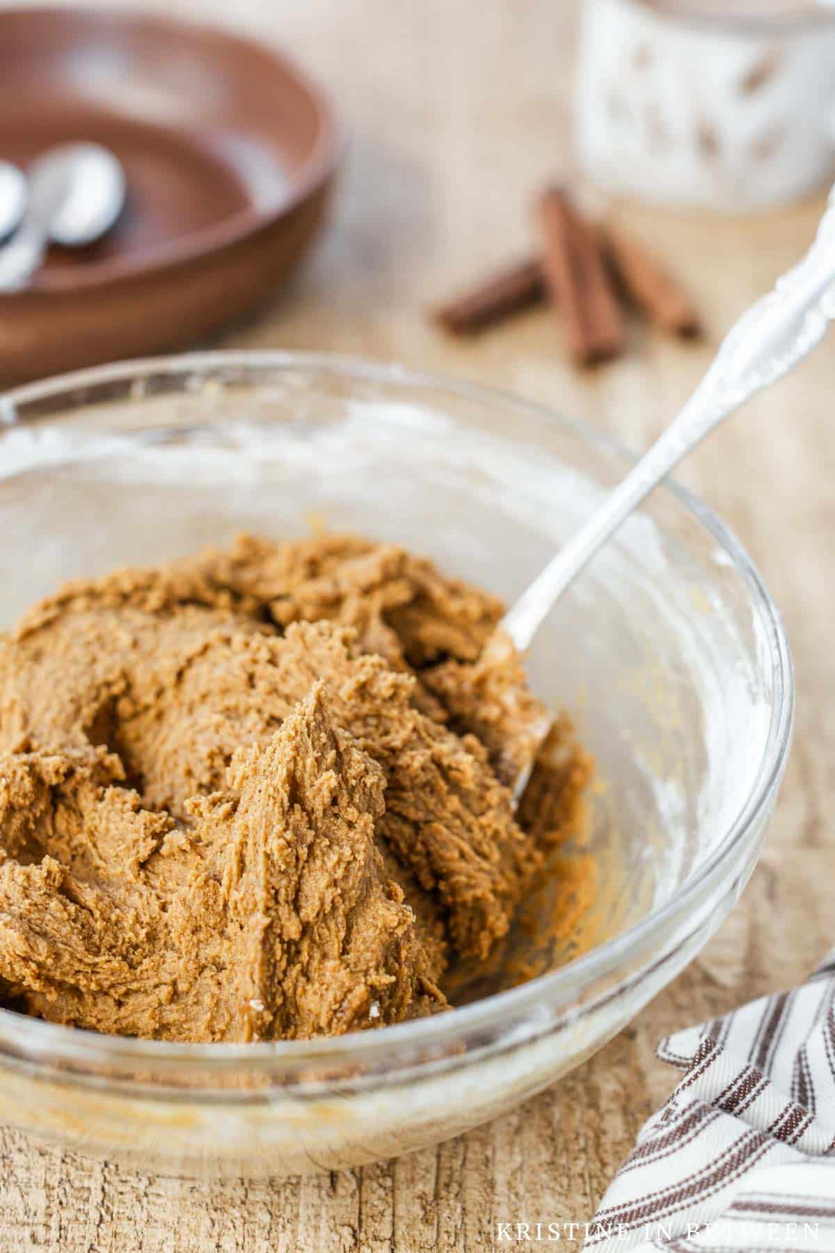 Edible gingerbread cookie dough mixed up in a glass bowl with a spoon.