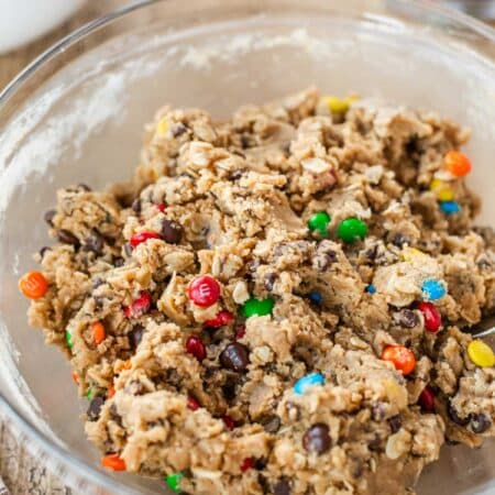 Edible cookie dough with chocolate chips and mini M&Ms in a glass bowl.