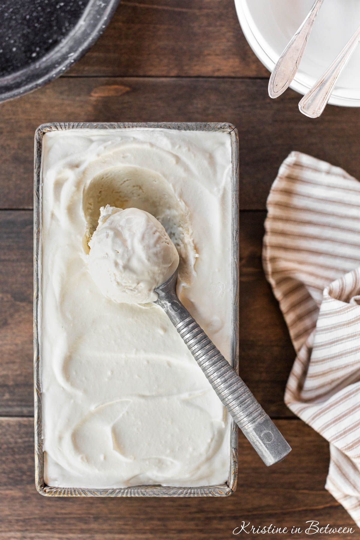 Vanilla no-churn ice cream in a loaf pan with a scoop on top.