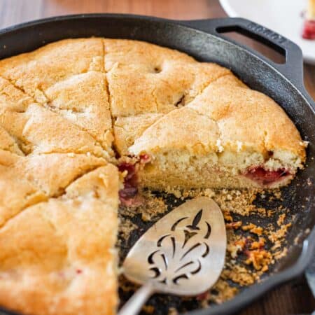 A strawberry skillet cake in a cast iron pan with an antique spatula.