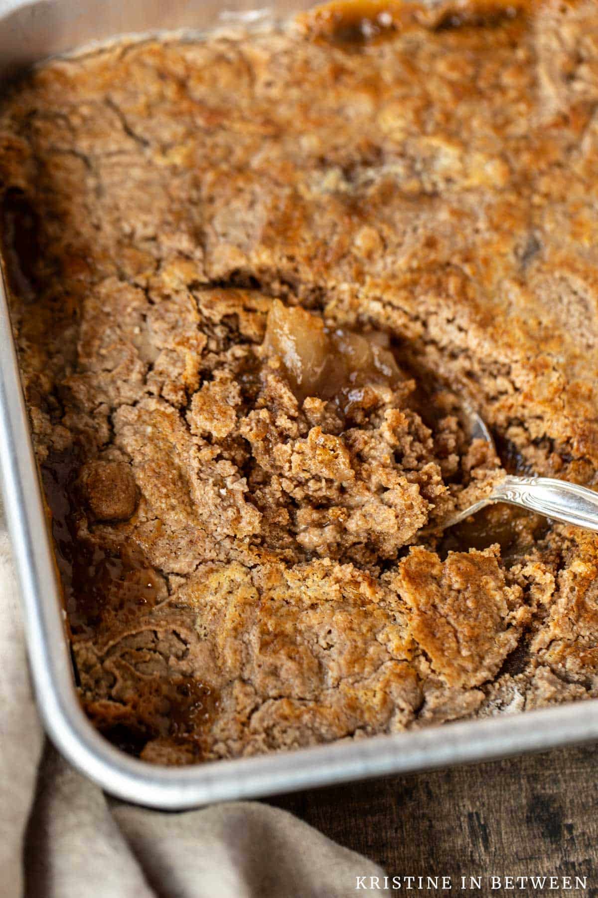 Dump cake in an aluminum pan with a spoon in the middle.