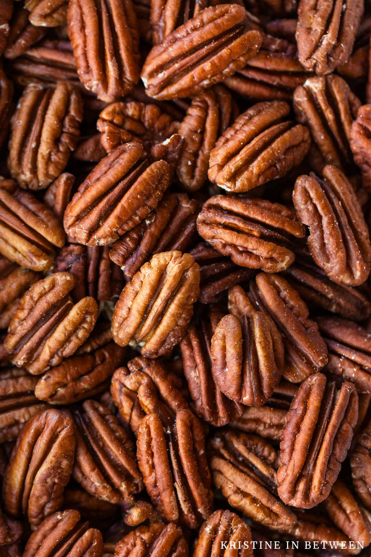 A bunch of pecans in a bowl showing their detail.
