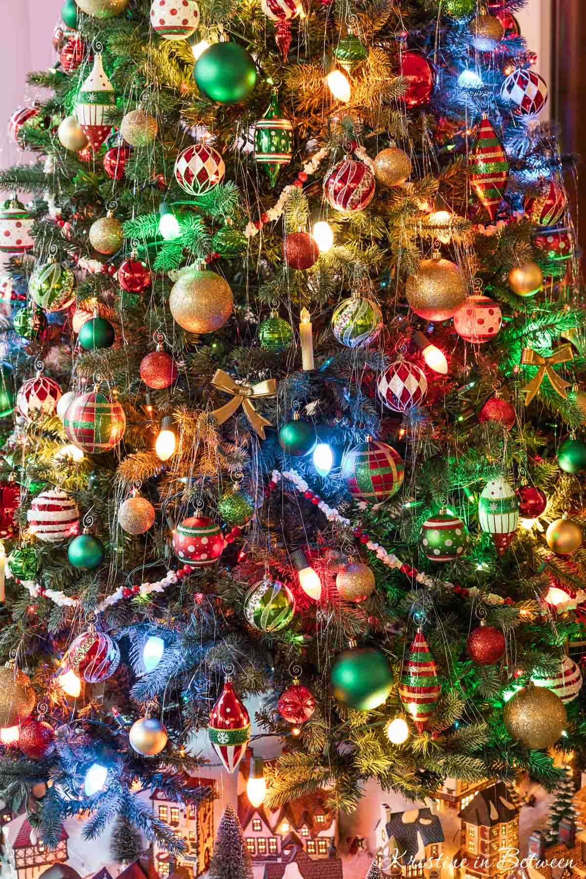 A brightly colored Christmas tree with popcorn garland and tinsel.