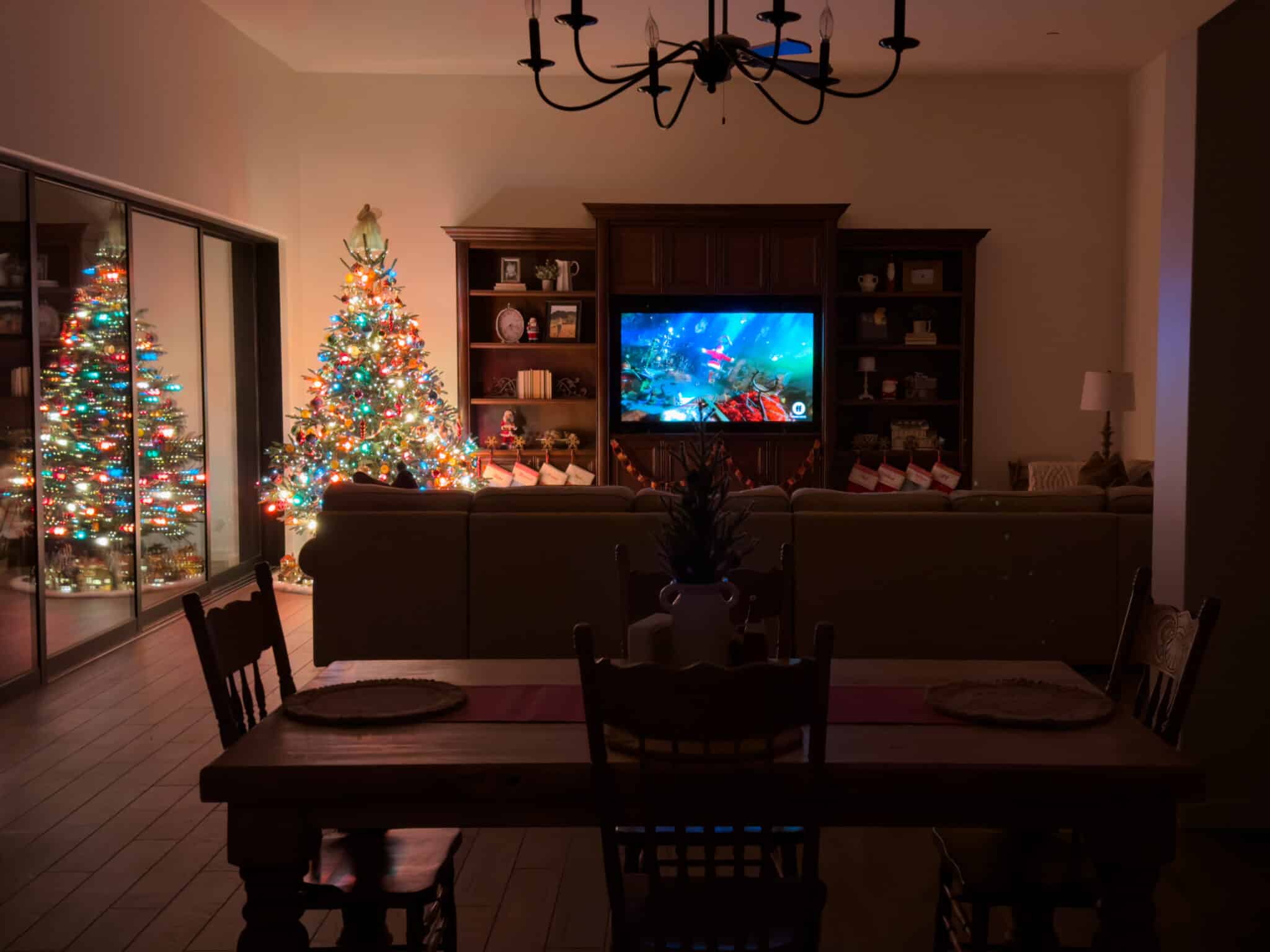 A dark house with a Christmas tree with multicolored lights in the corner.