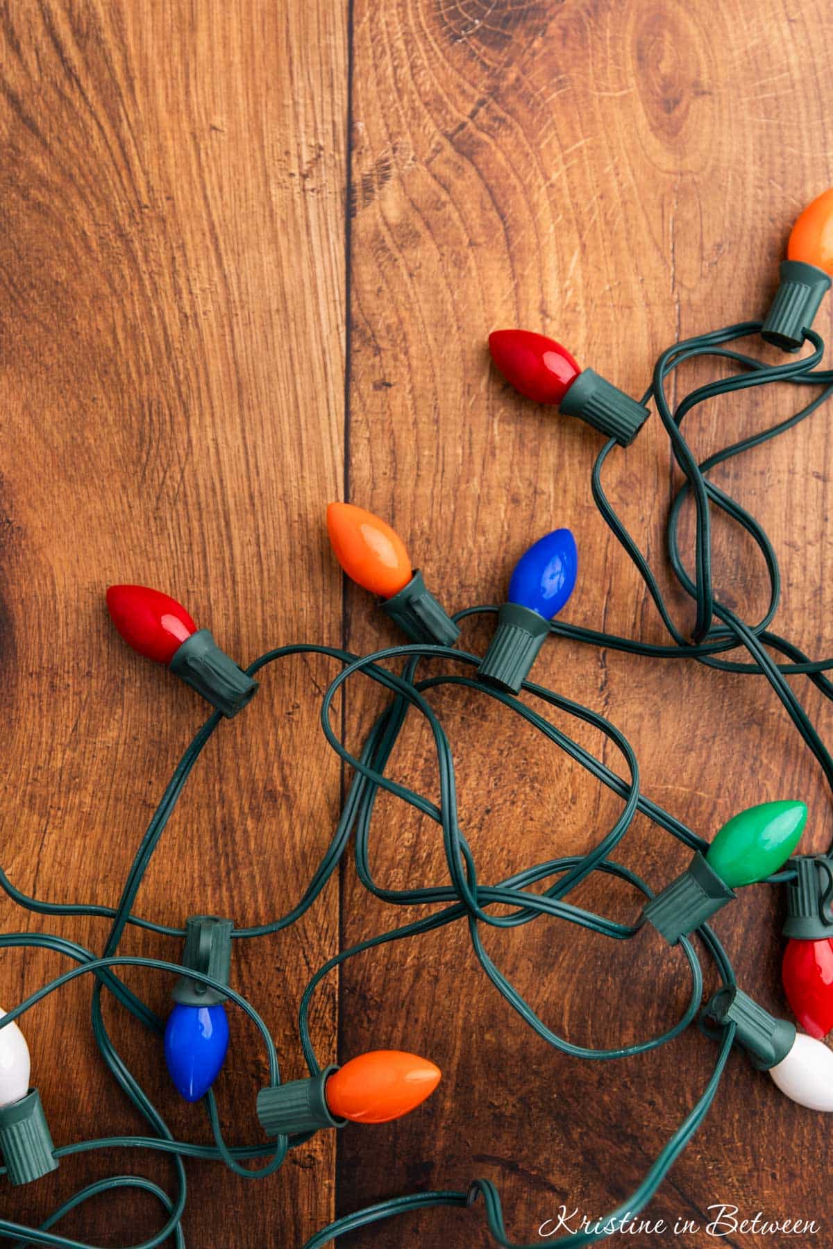 A strand of multicolored lights on a wooden board.