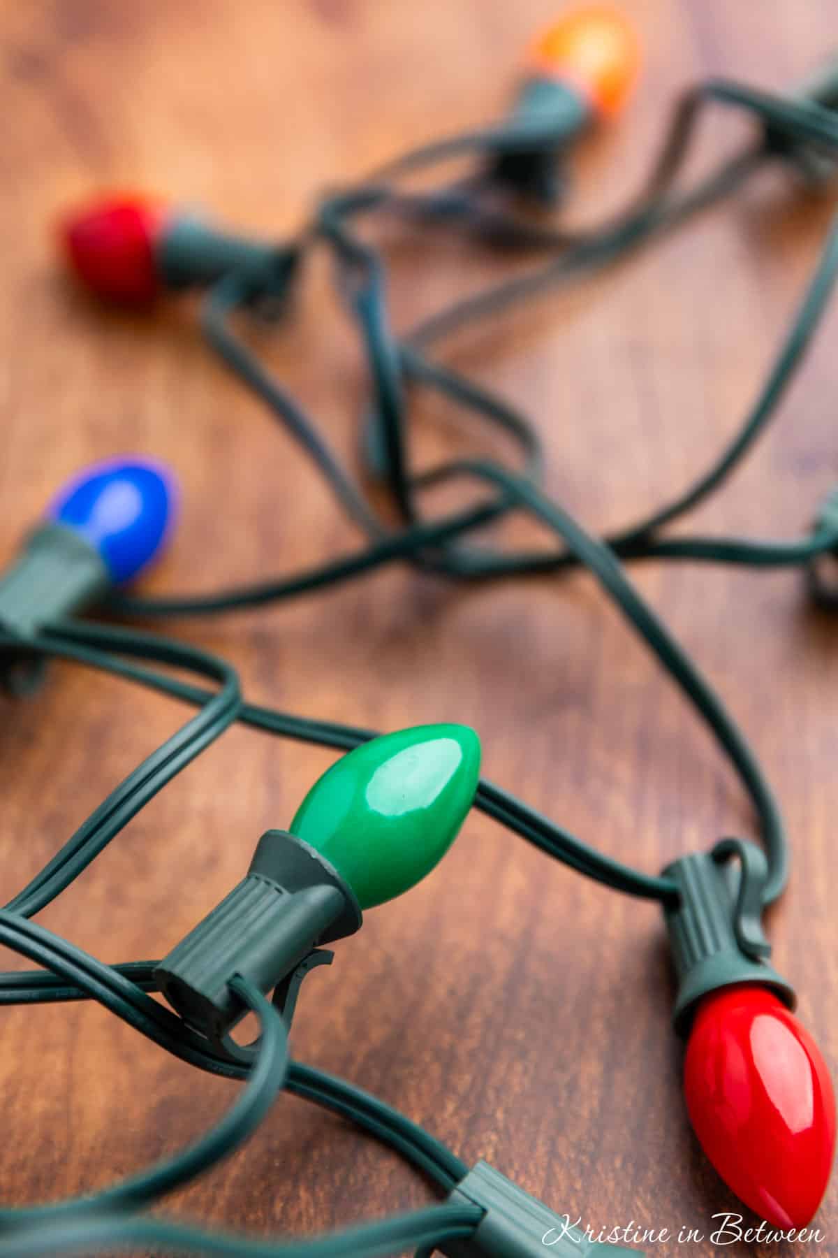 A strand of multicolored lights on a wooden board.