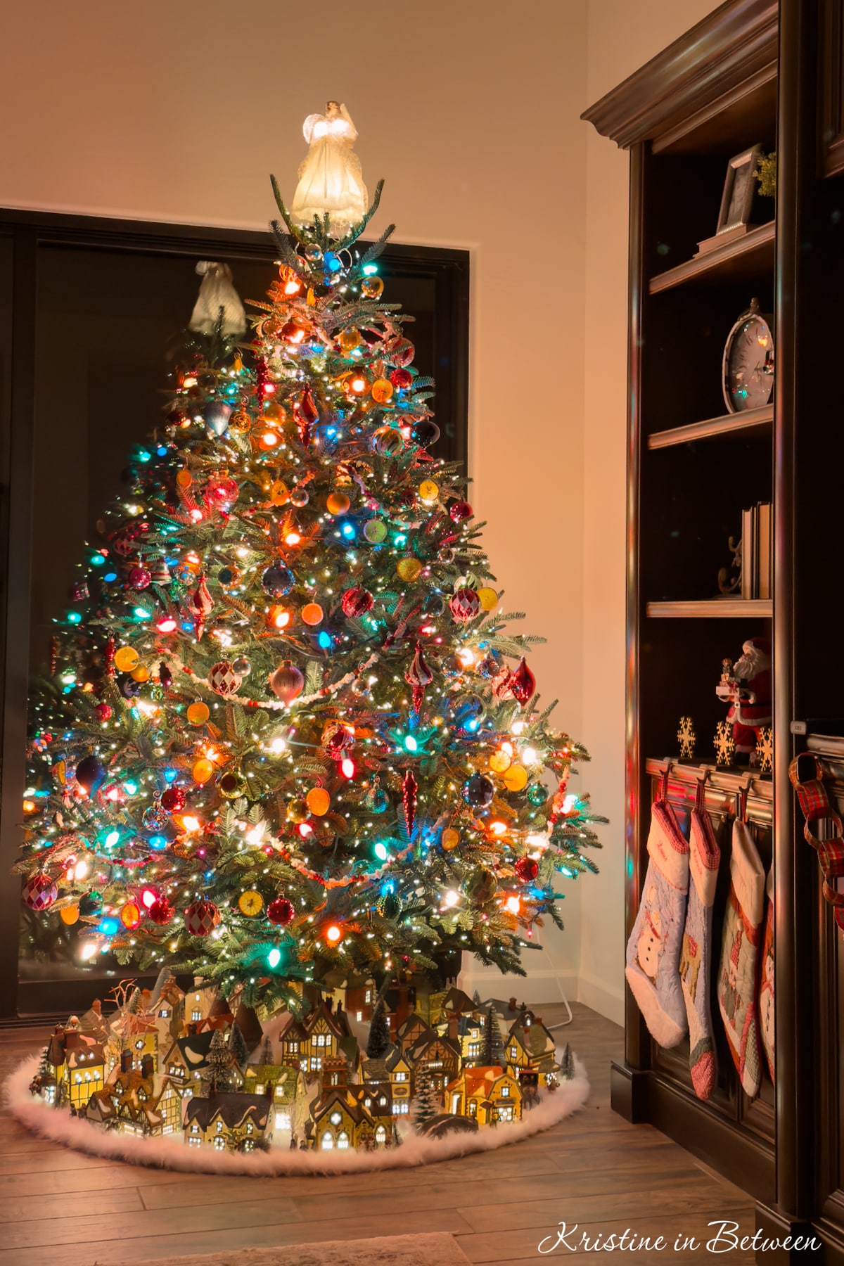 A Christmas tree at night with colored lights and an angel on top.