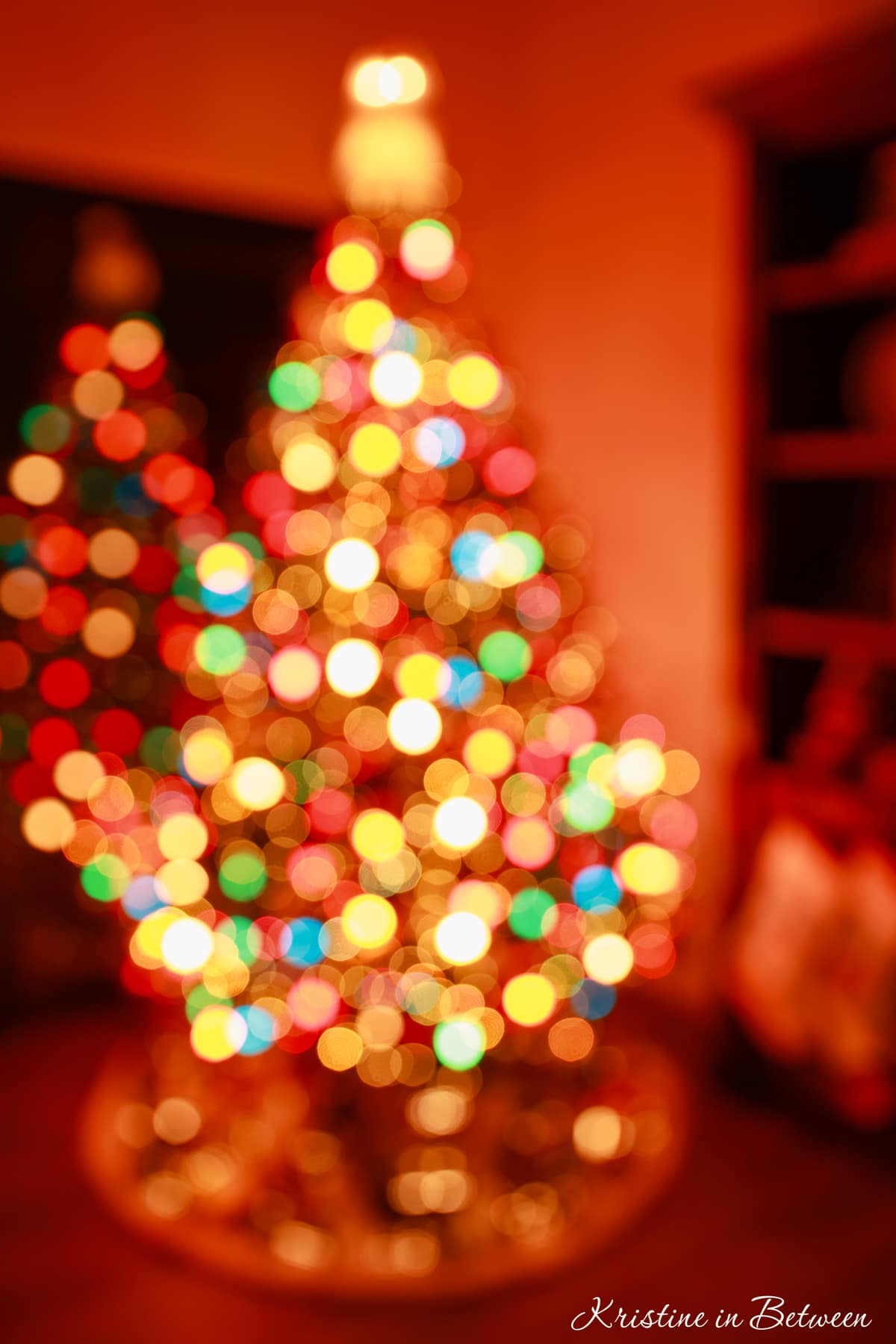 A bokeh Christmas tree with multicolored lights in a dark room.